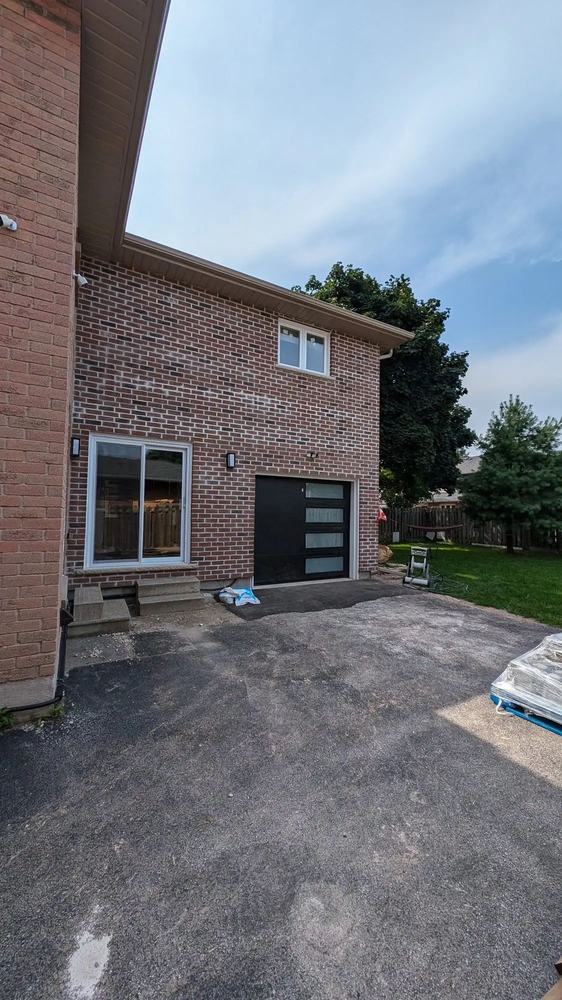 The completed two-storey addition in matching brick, with a new garage door and windows above