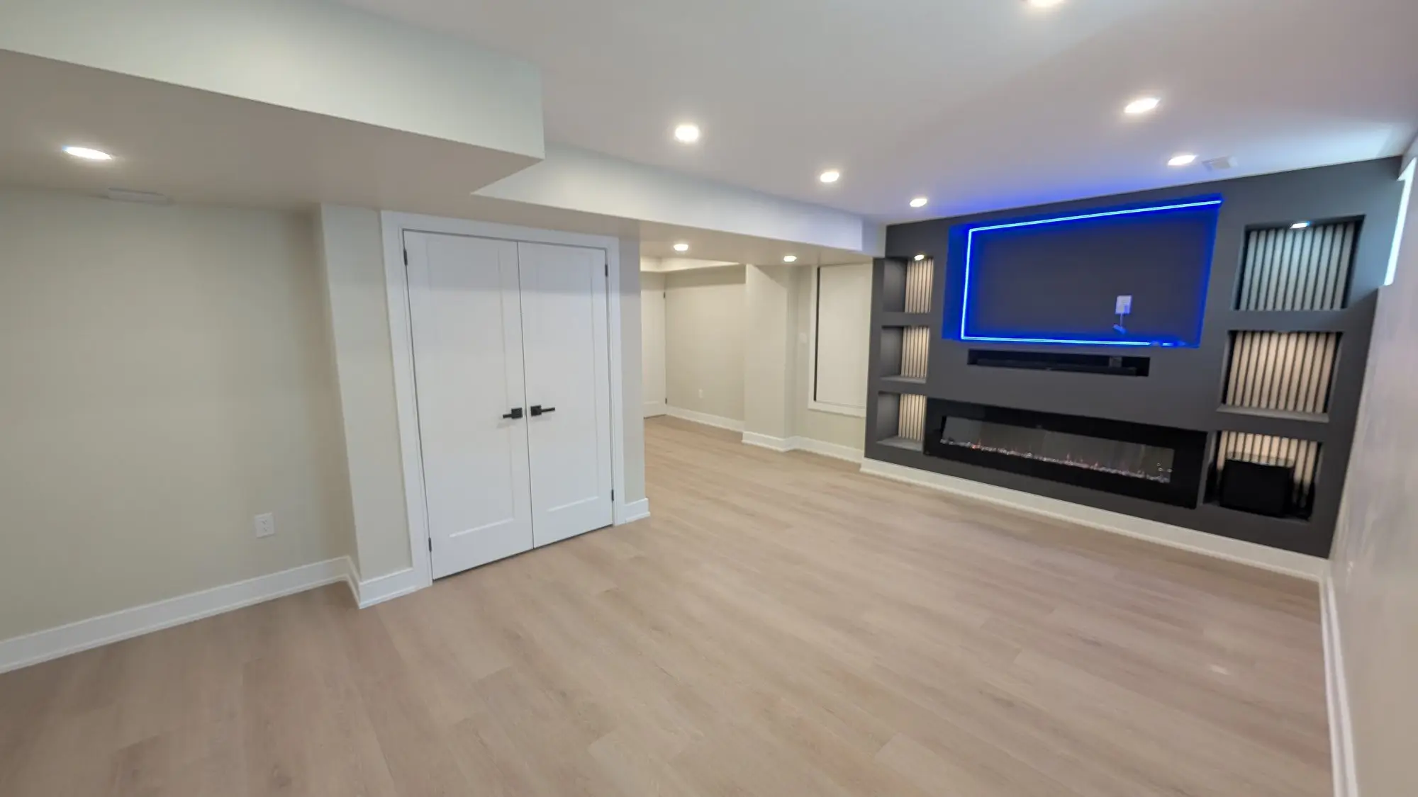 The finished basement rec room with a built-in media wall, linear fireplace and integrated lighting