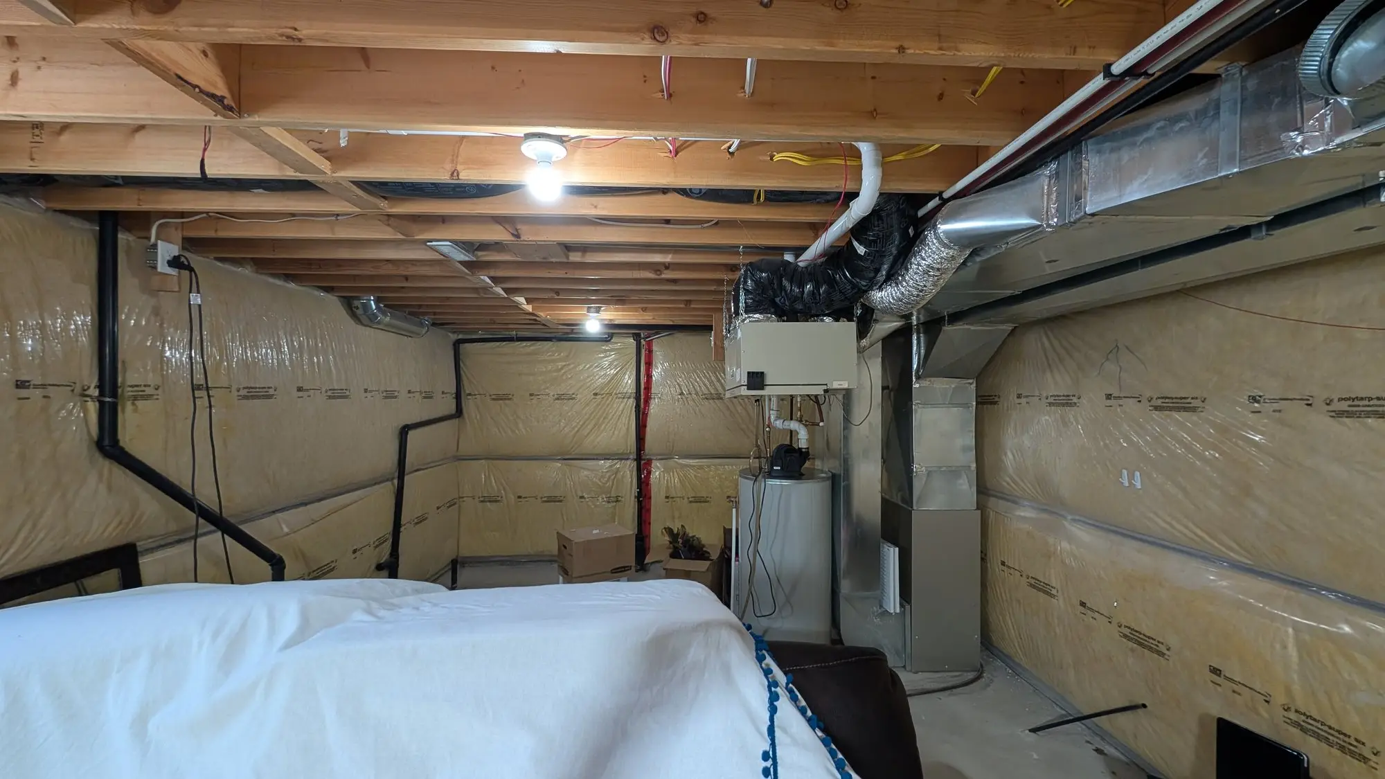 The unfinished basement before work, with exposed joists and insulated stud walls