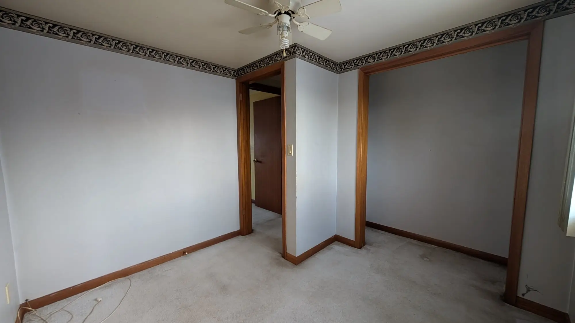 Original bedroom with dark wood trim, carpet and wallpaper border