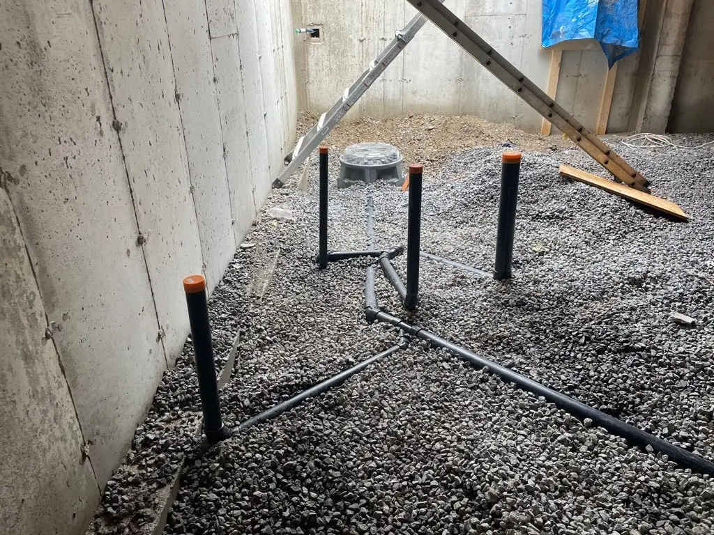 Under-slab drain lines laid in gravel across the basement floor