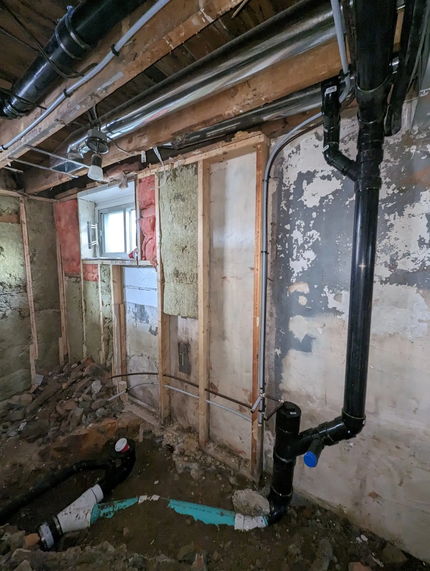 New drain and supply lines run through the basement wall