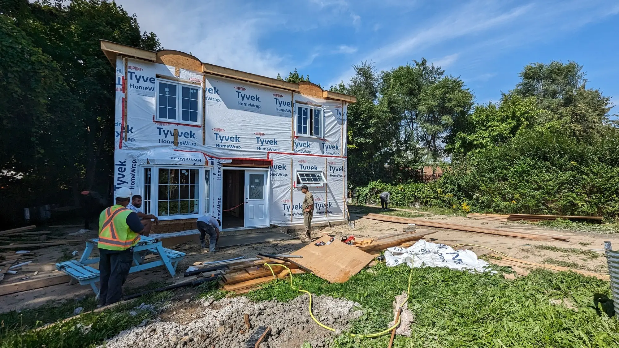 Exterior wrapped and windows set, with the crew working on the front entry