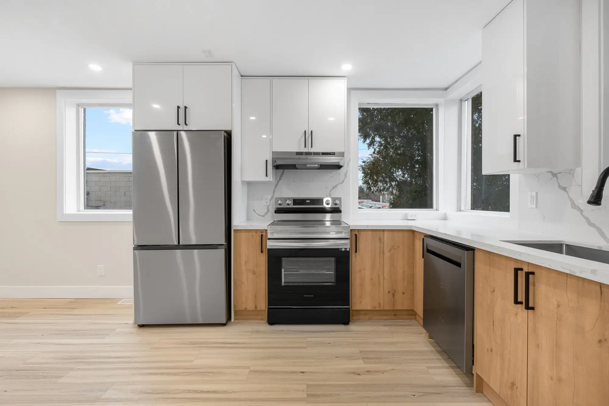 Main floor kitchen with quartz counters, wood-tone lowers and stainless appliances