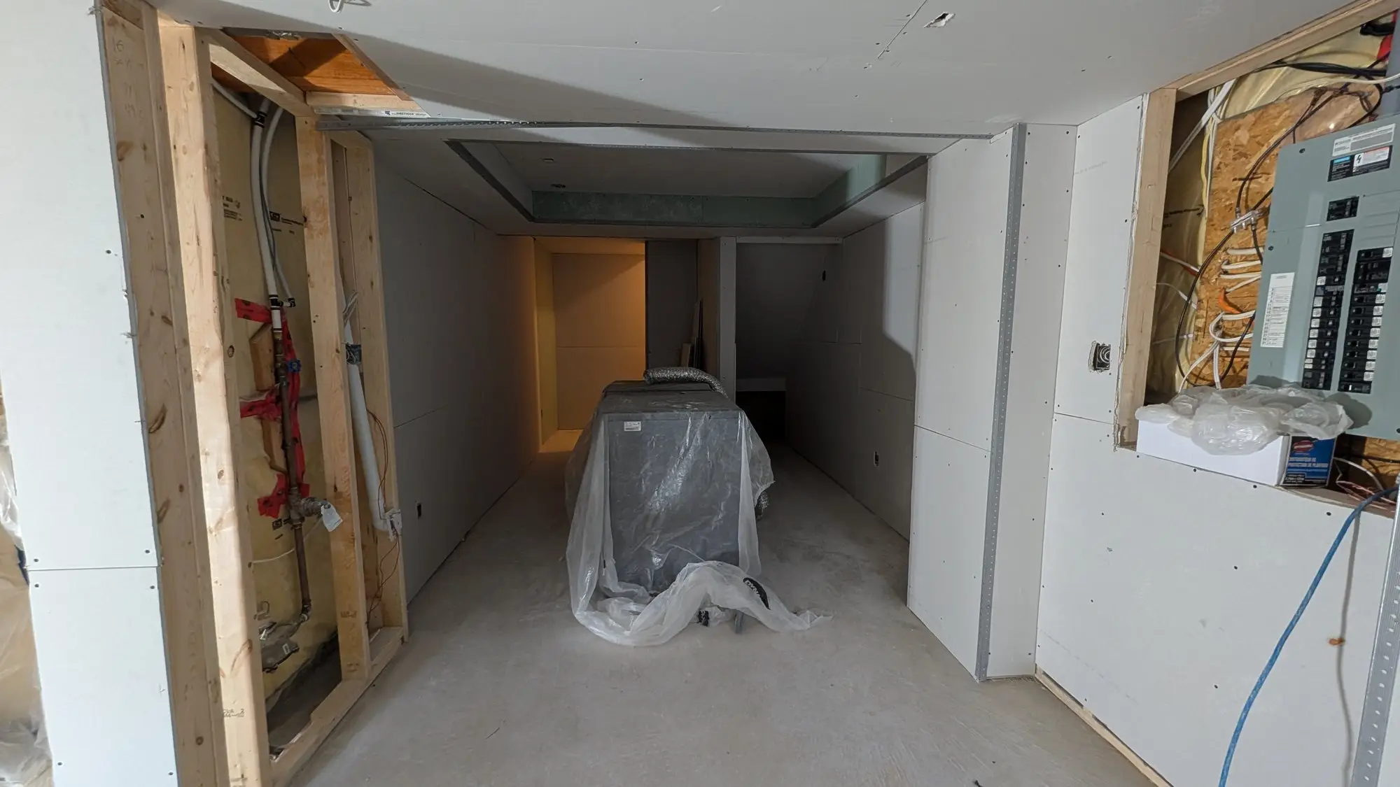 Drywalled corridor with services still exposed at the panel