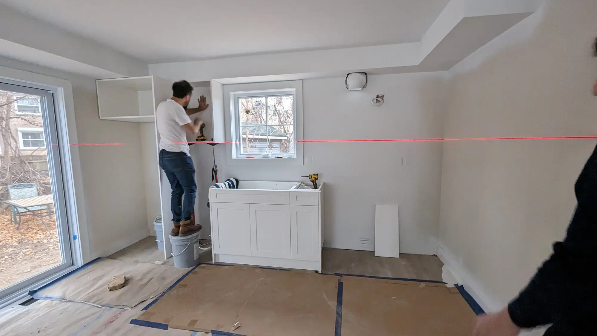 Kitchen cabinets being levelled and installed against a laser line