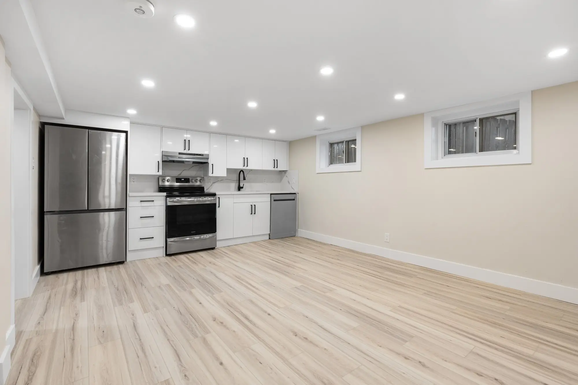 Basement unit living area with pot lights and plank flooring
