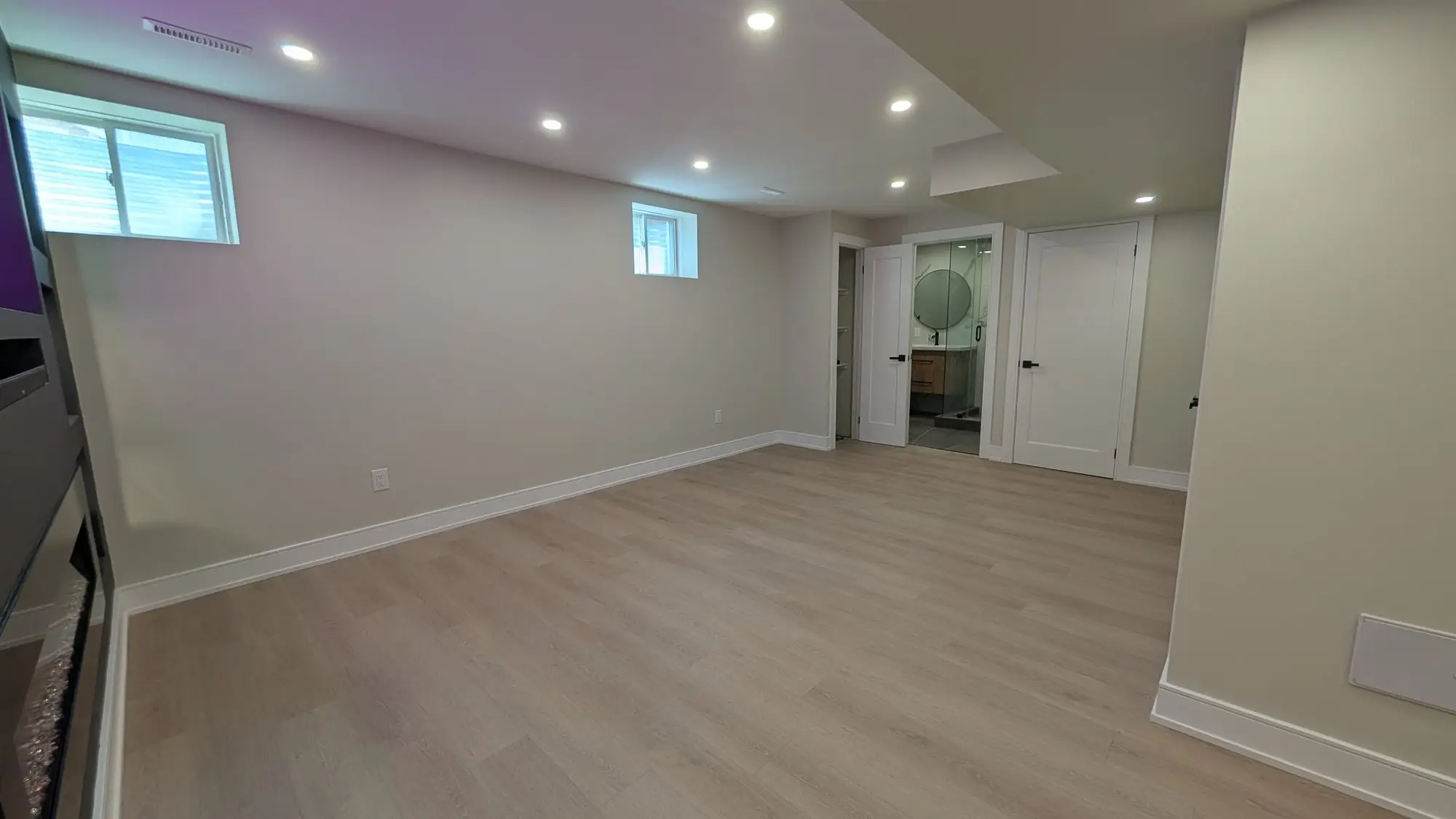 Finished open room on the lower floor with plank flooring and pot lights