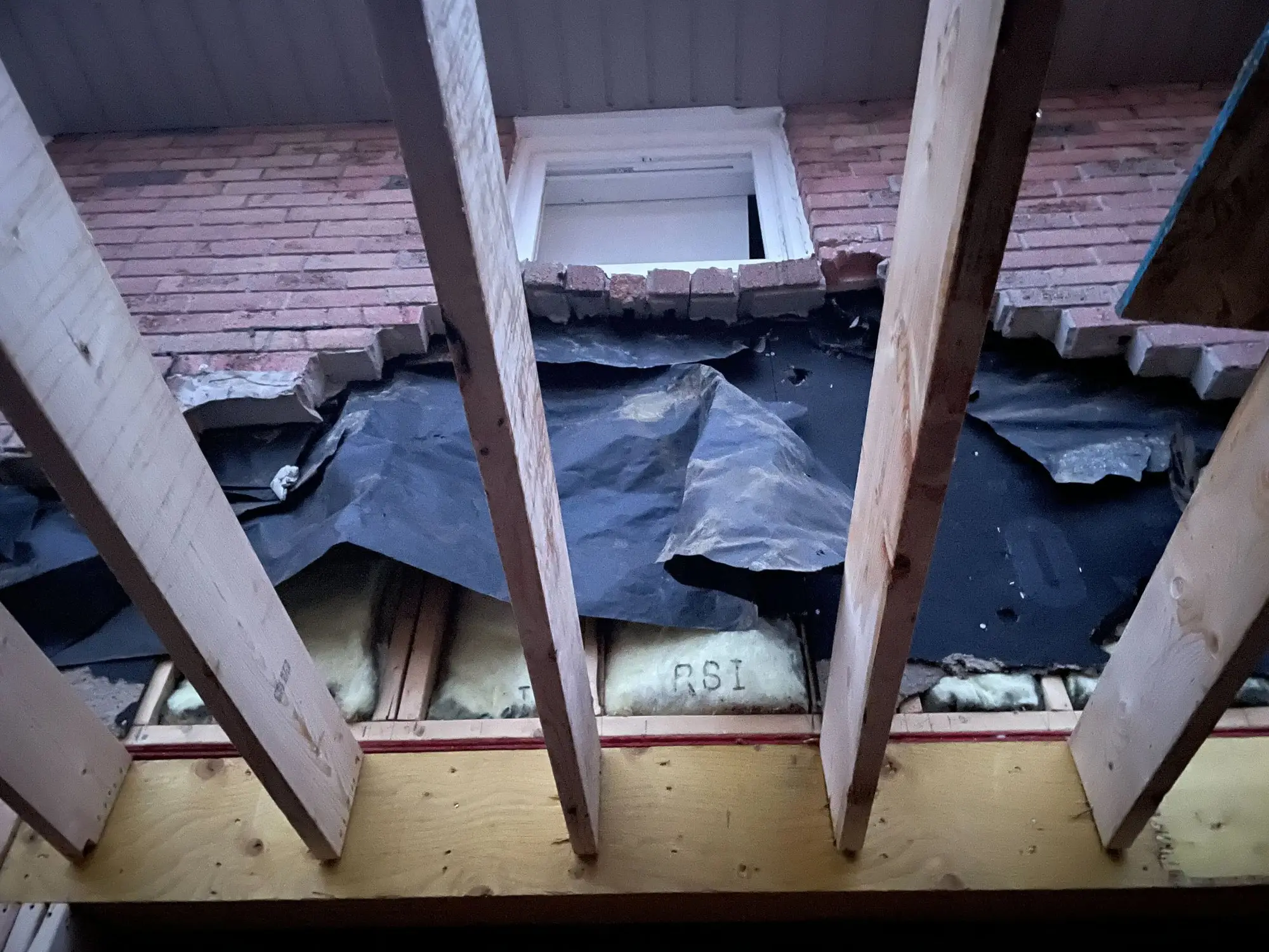New roof framing cut into the existing brick wall of the house