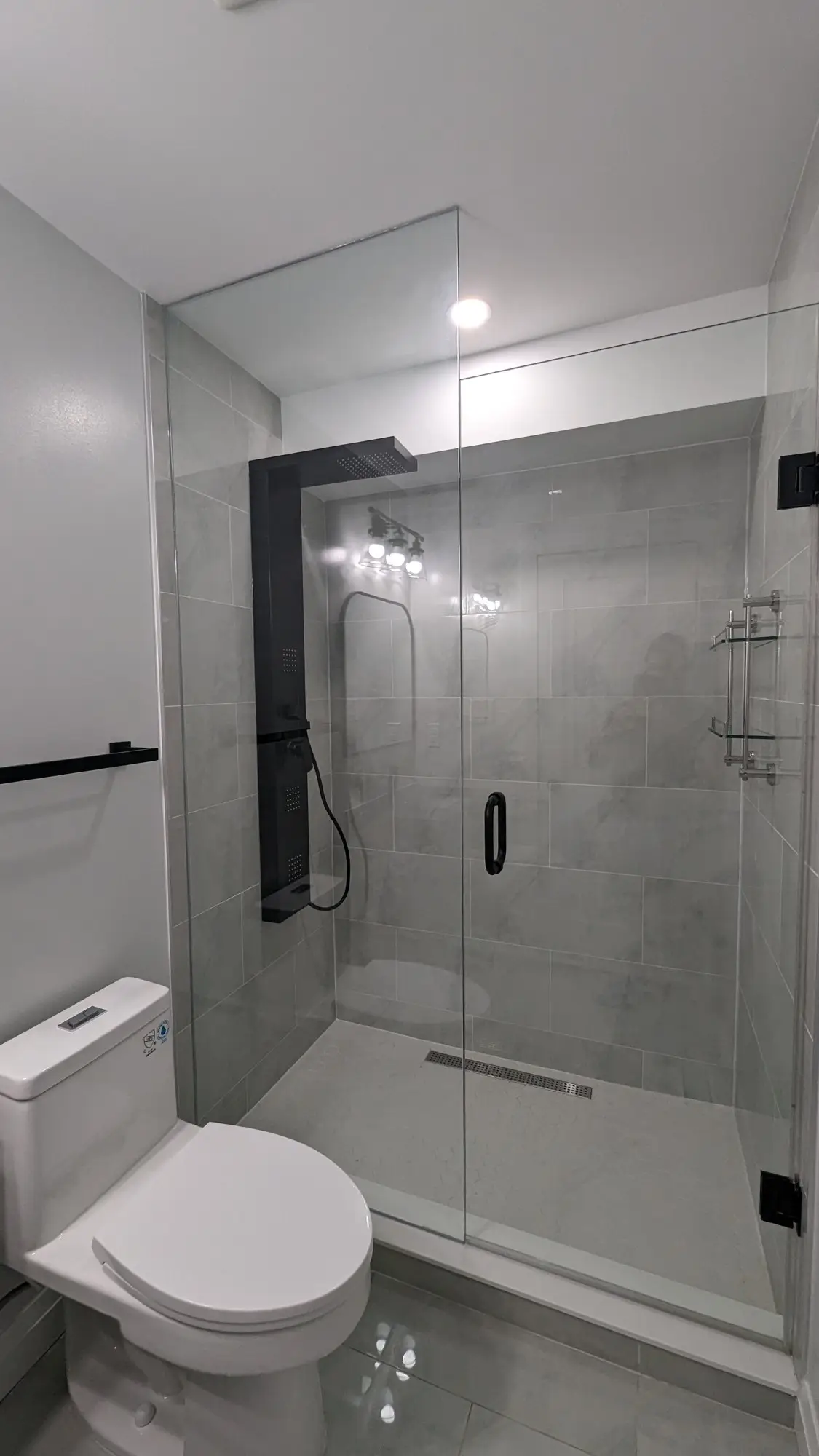Finished bathroom with glass shower enclosure and tiled walls