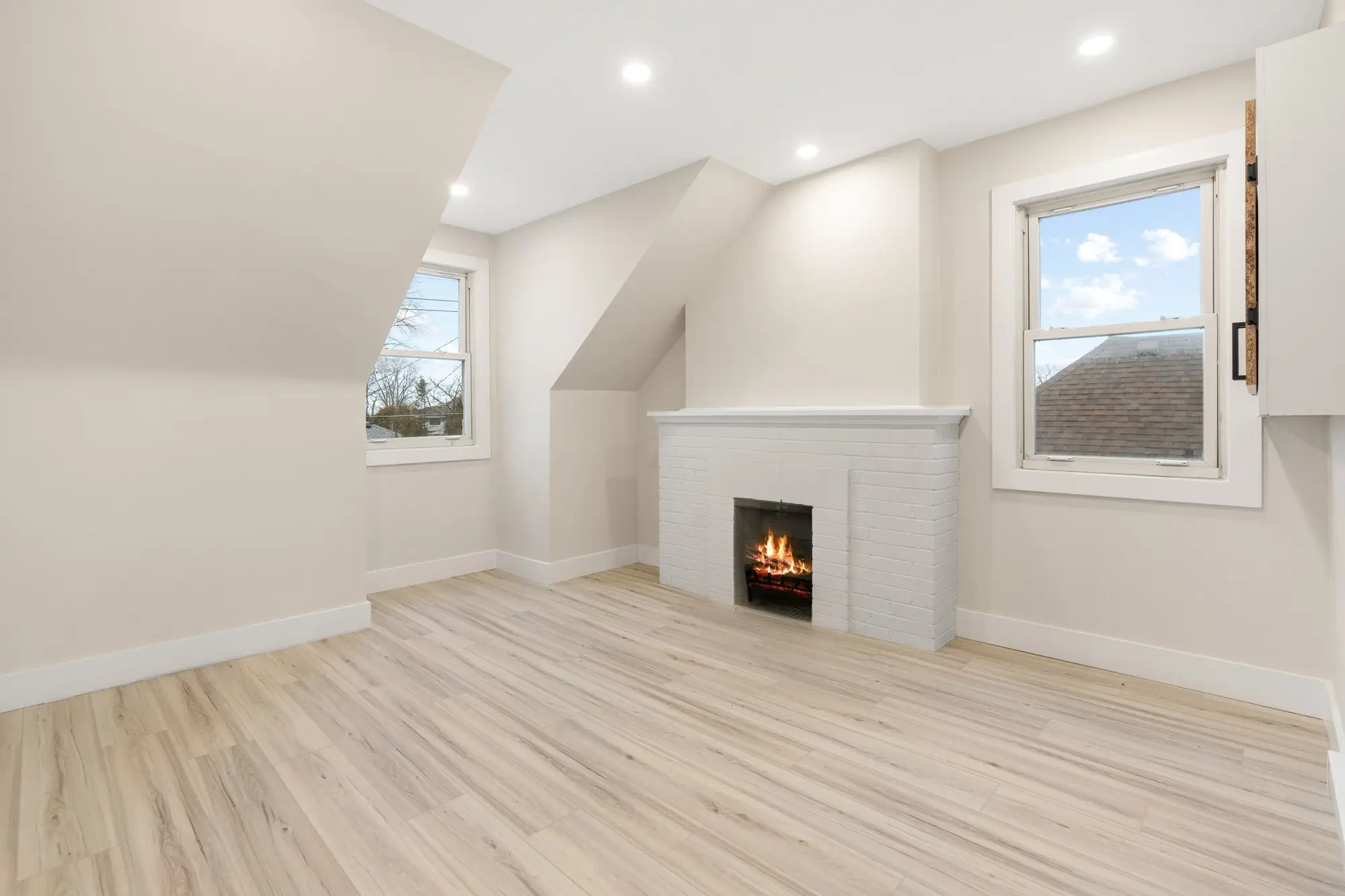 Second floor living space with sloped ceiling and electric fireplace