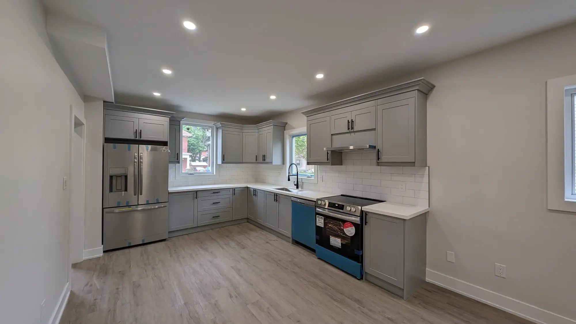Finished kitchen seen from the open living space, with quartz counters and subway tile