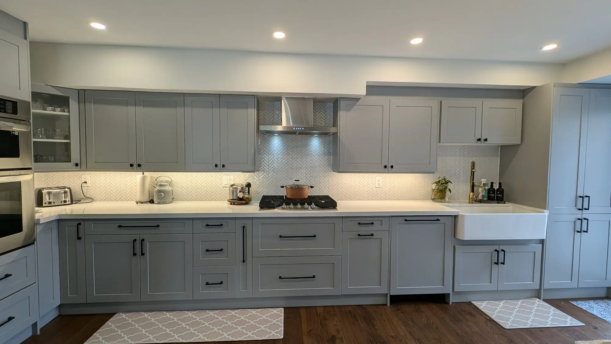 Long run of grey shaker cabinetry with quartz counters and undercabinet lighting
