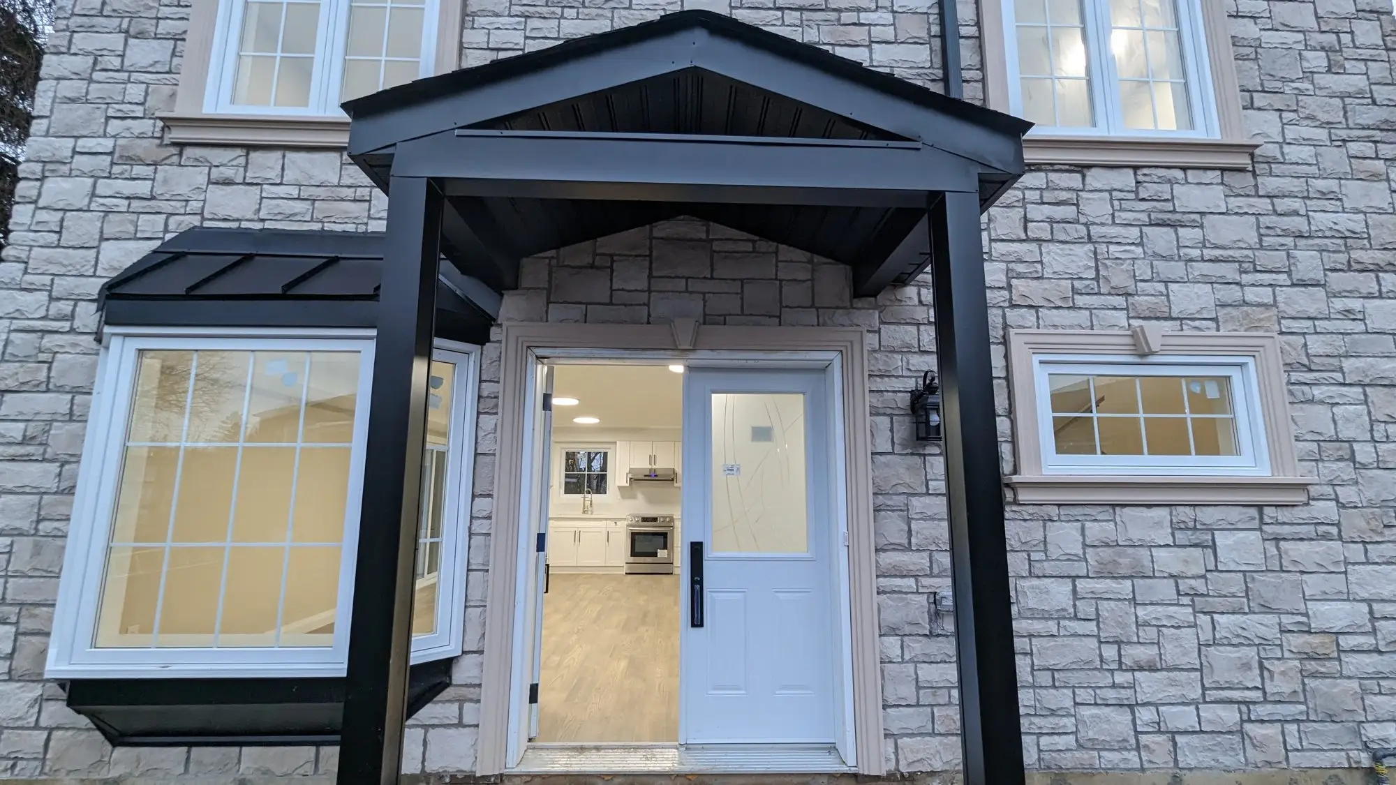 Finished garden suite front entry with stone surround, bay window and covered porch