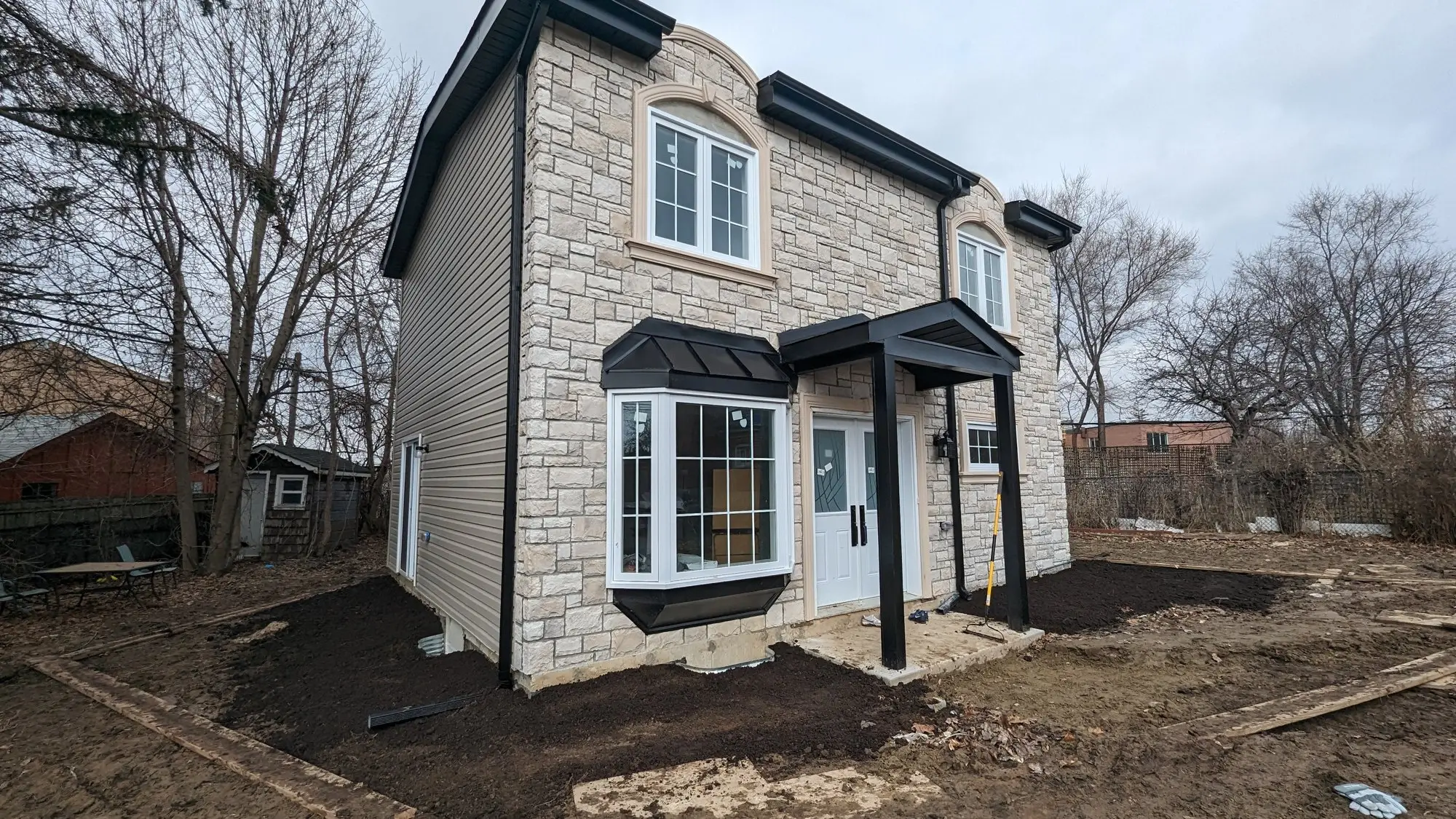 Completed two-storey garden suite in a Scarborough back yard, finished in stone and siding