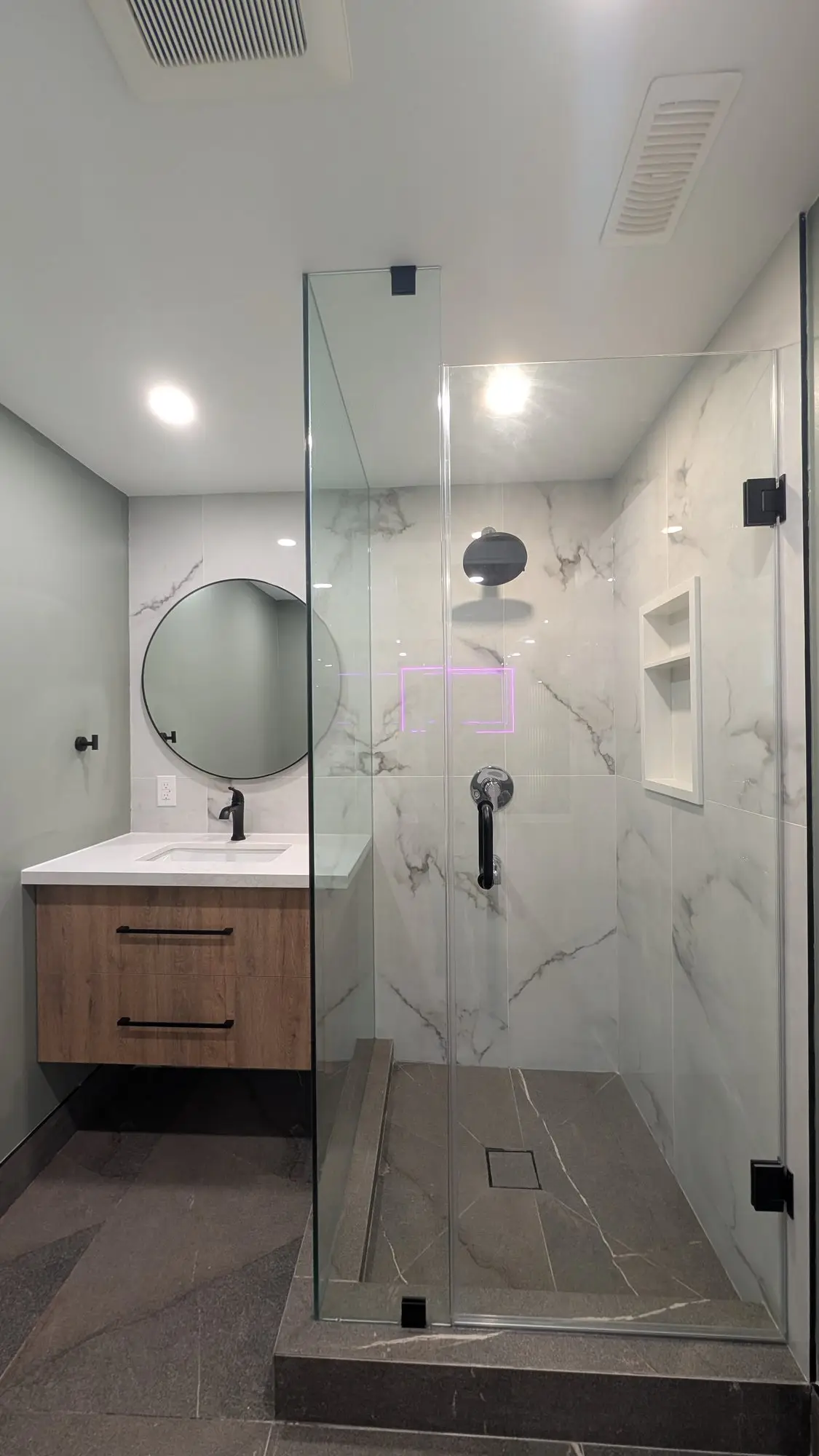 Walk-in shower with glass enclosure and floating vanity