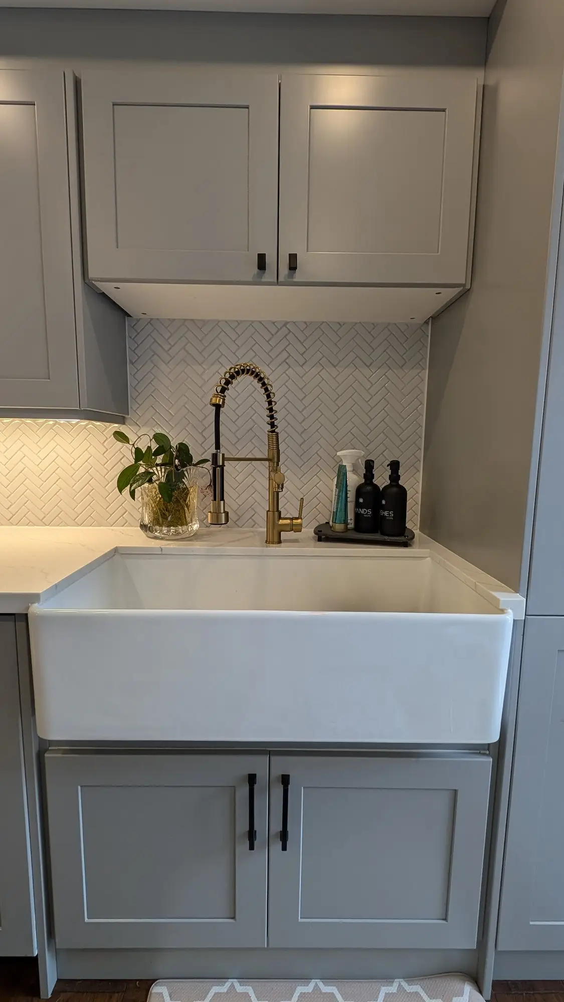 Apron-front sink with brass tap against the quartz counter