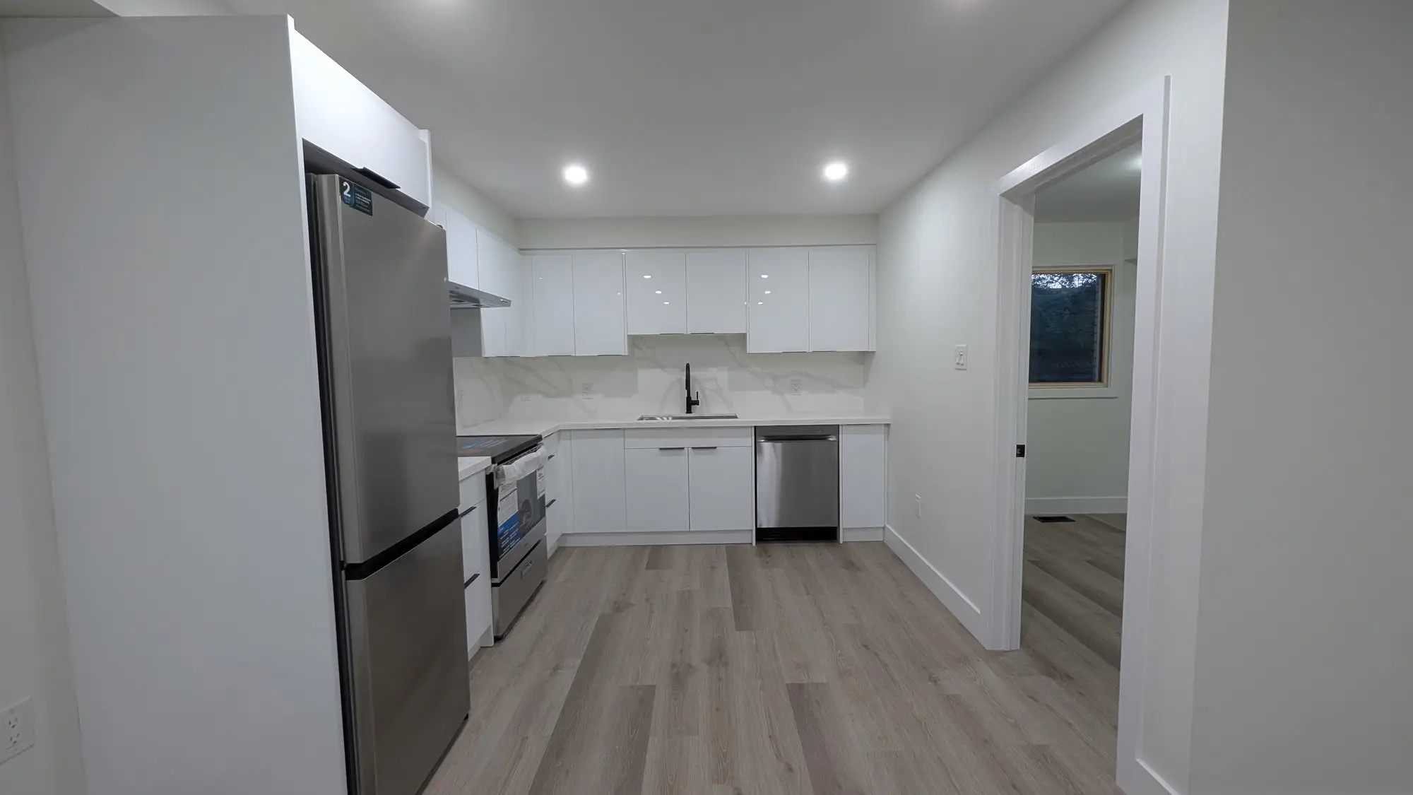 Second unit kitchen with white cabinets and stainless appliances