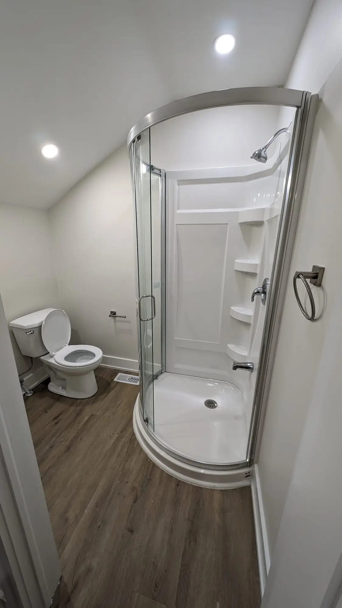 Finished bathroom with a corner shower enclosure under the sloped ceiling