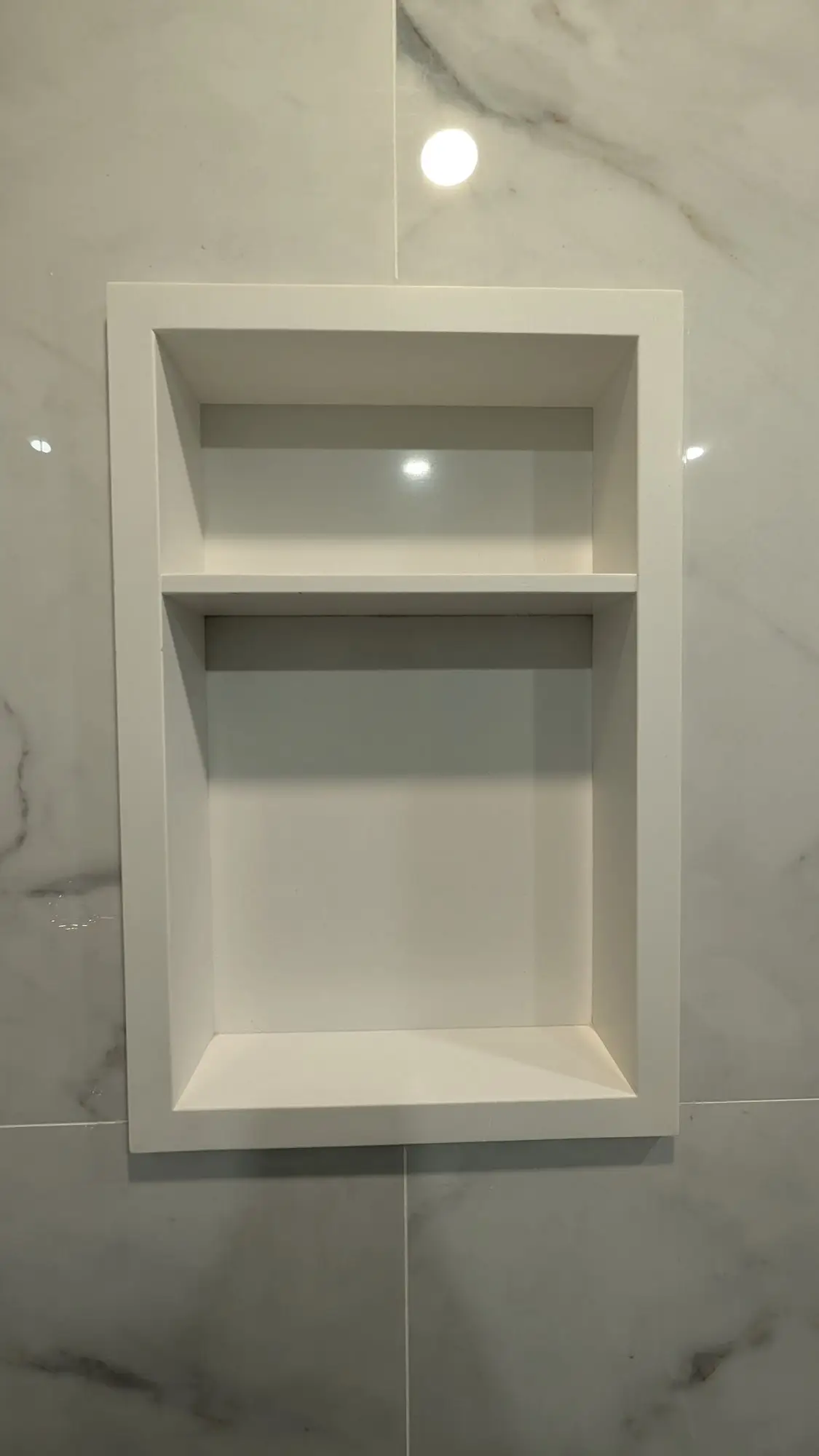 Recessed tiled niche built into the shower wall