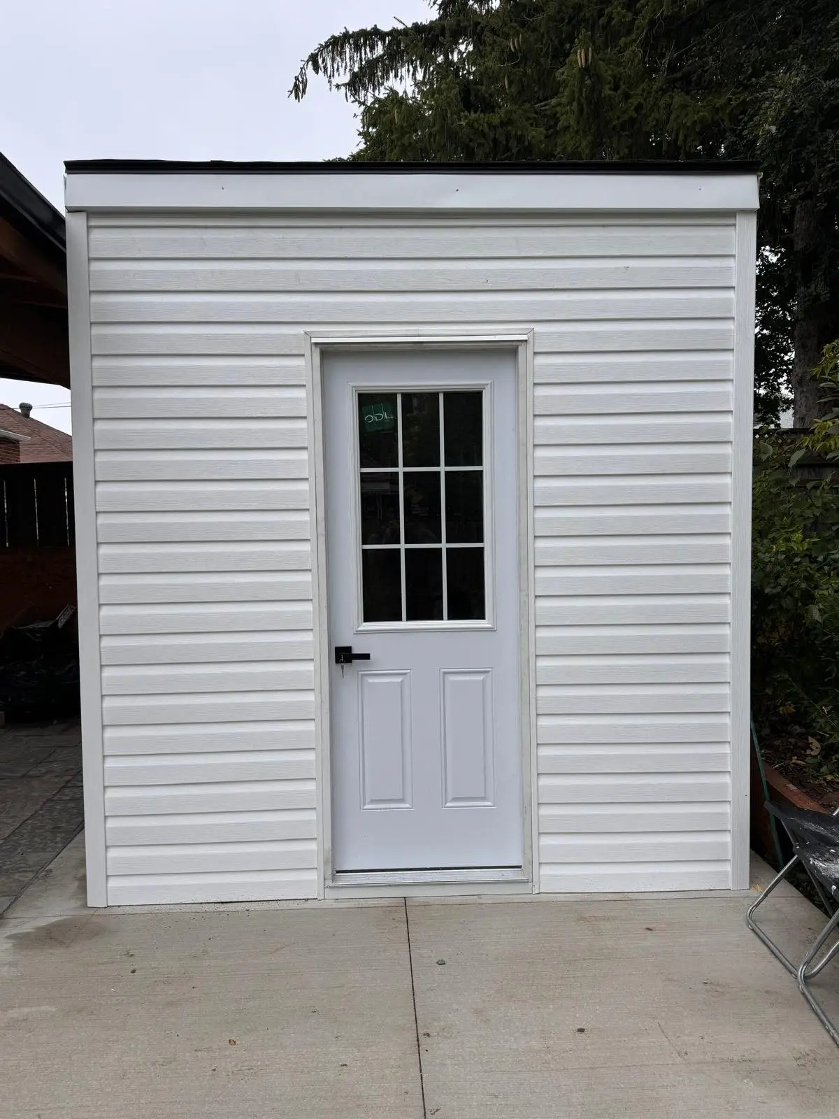 The finished garden outbuilding in white siding with its own entry door