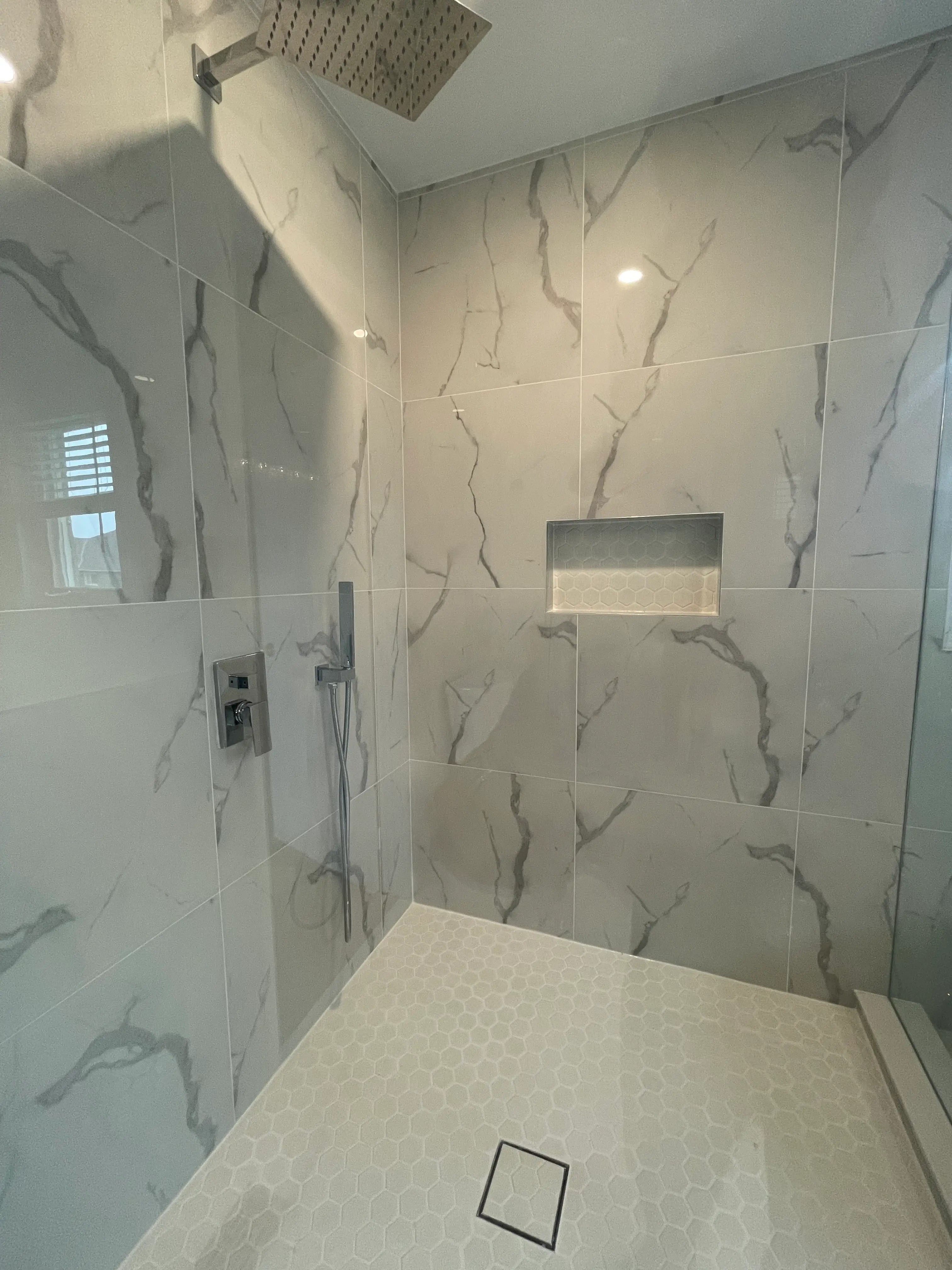 Large-format marble-look porcelain tile in a custom shower