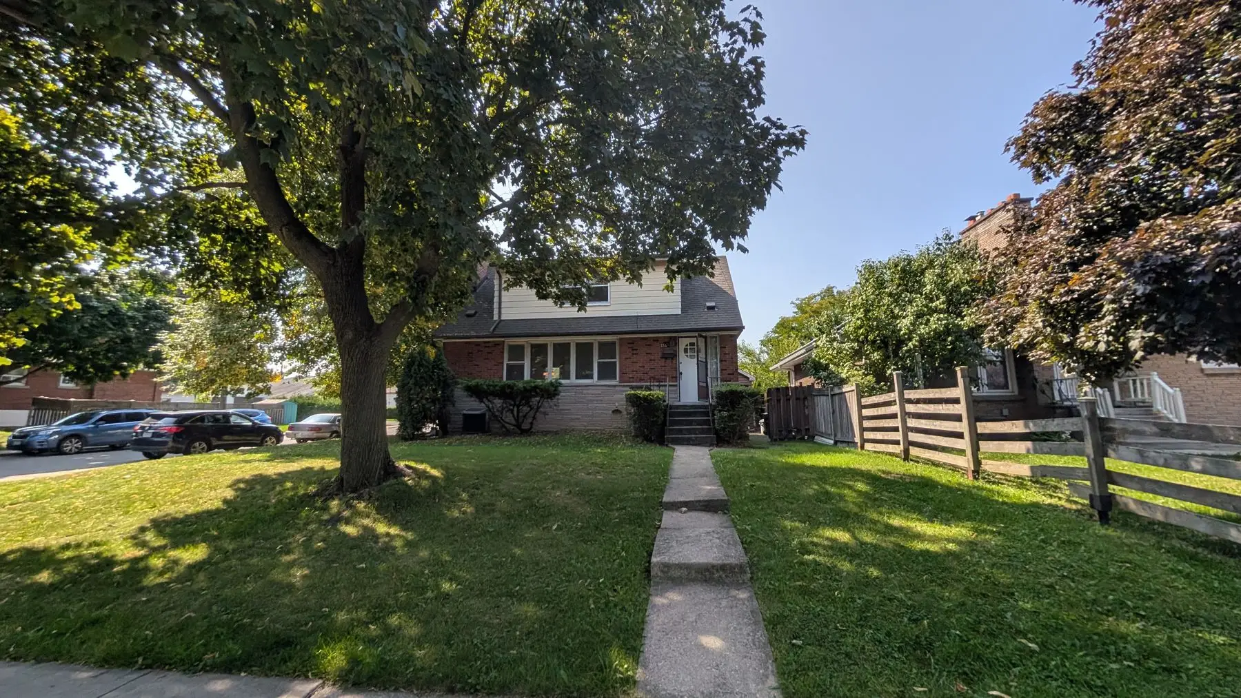 Before — Exterior front view of a two-story brick house with a front walkway and mature tree.