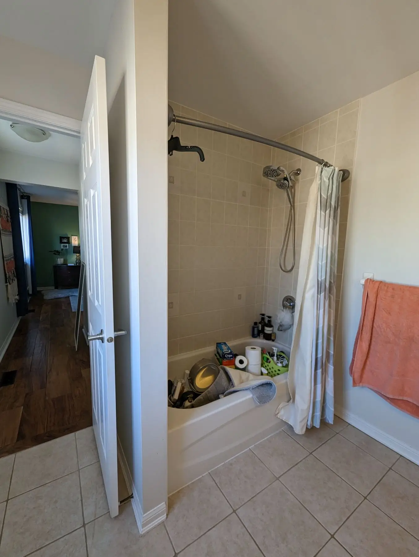 Before — View of a bathroom showing tub, shower surround, and open doorway looking into hallway.