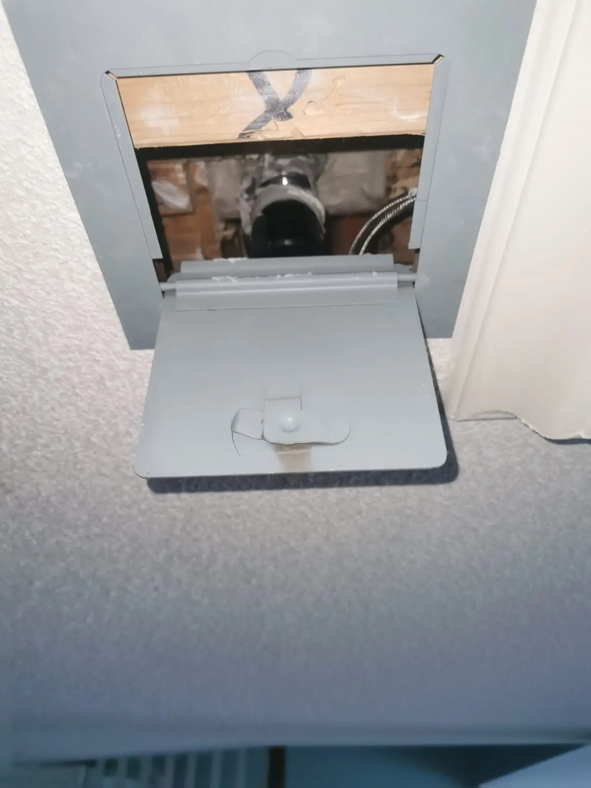 Rough-in — Close-up of an open wall access box revealing interior plumbing and wiring.