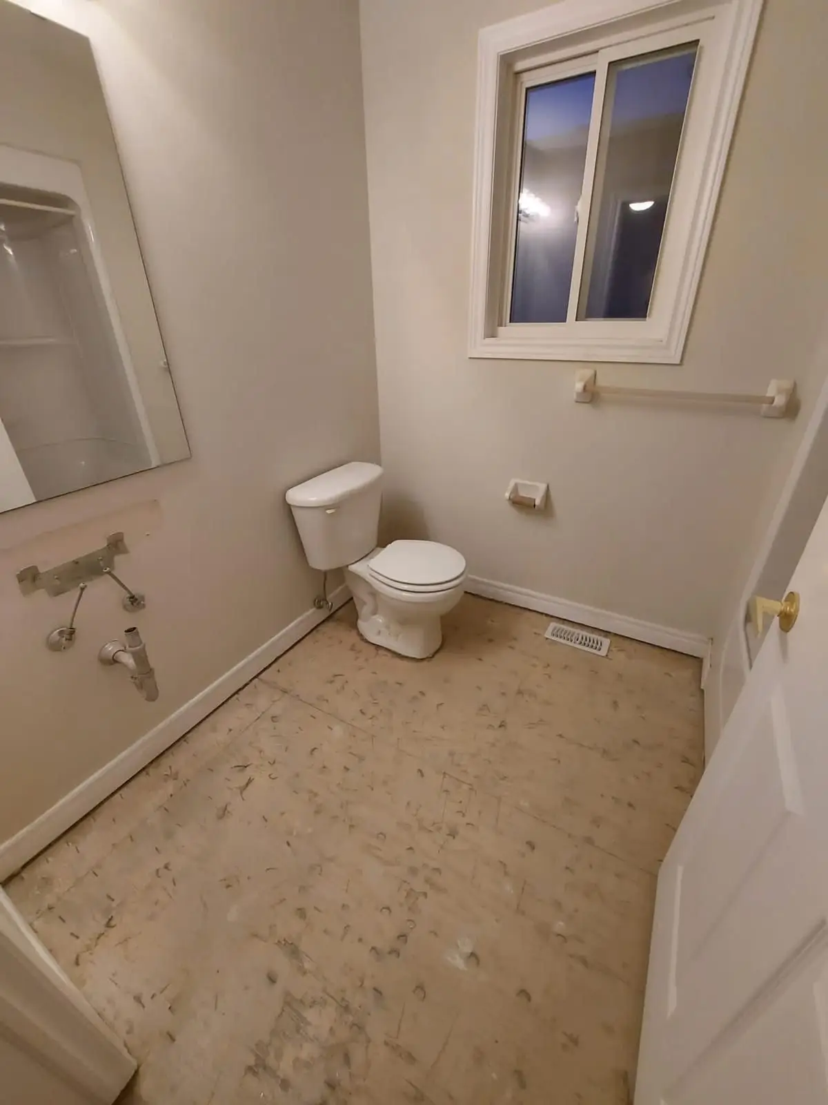Demolition — Bathroom during demolition with missing vanity, exposed subfloor, and toilet still installed.