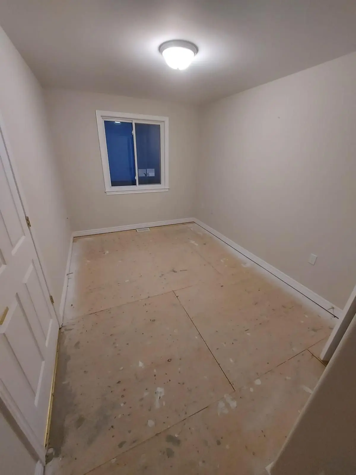 Insulation & drywall — Empty room with painted walls, trim, and subfloor awaiting flooring installation.