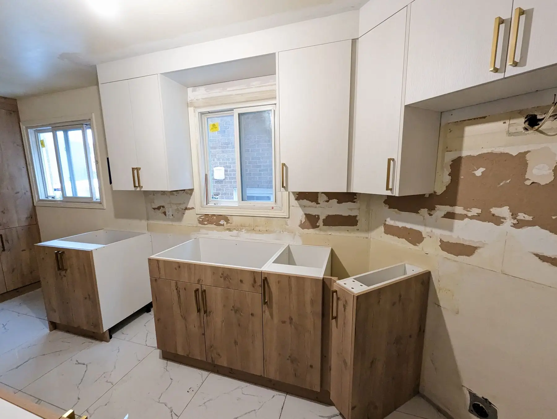 Finishing — Kitchen renovation in progress with lower and upper cabinets partially installed against unfinished walls.