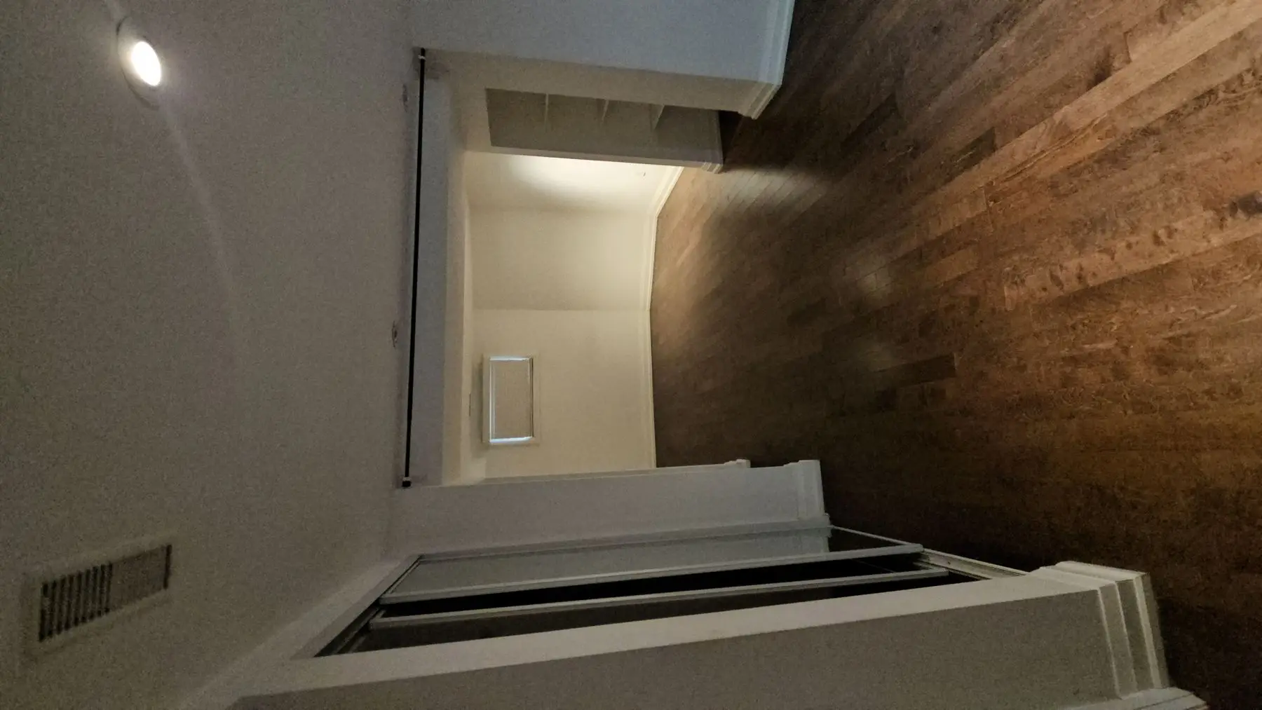 Finished — View of a finished living space with hardwood floors and white walls through a doorway.