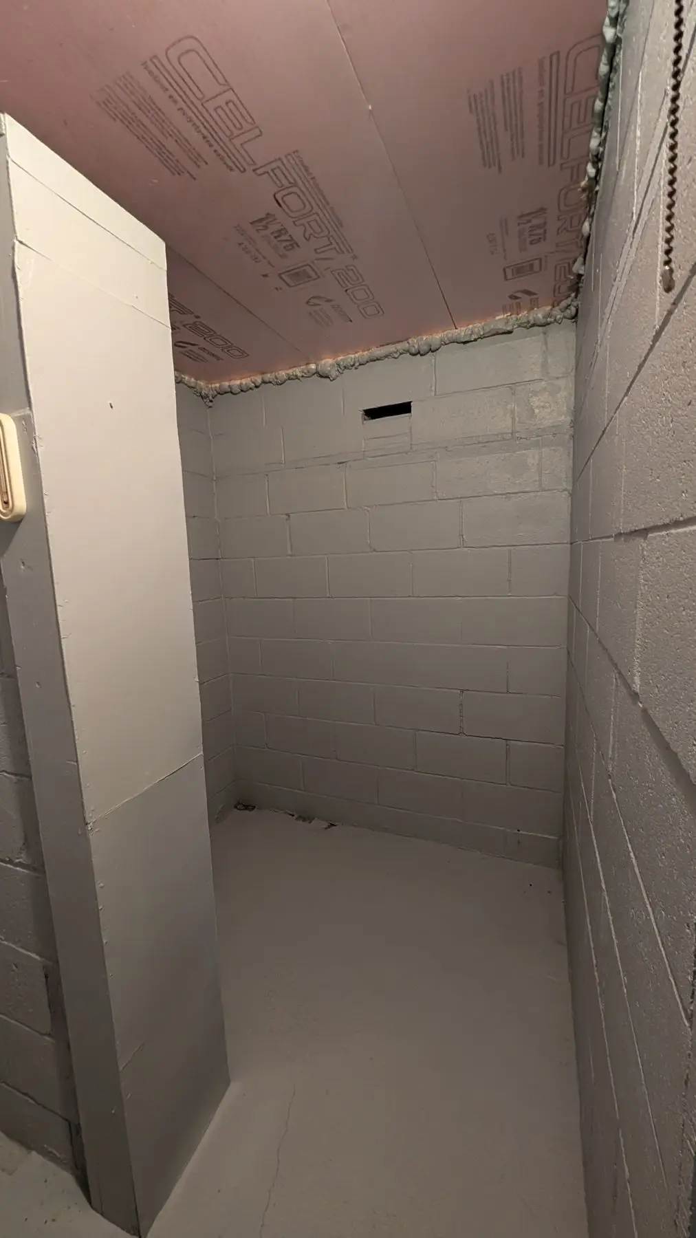 Insulation & drywall — Basement corner showing painted concrete block walls and rigid foam ceiling insulation.