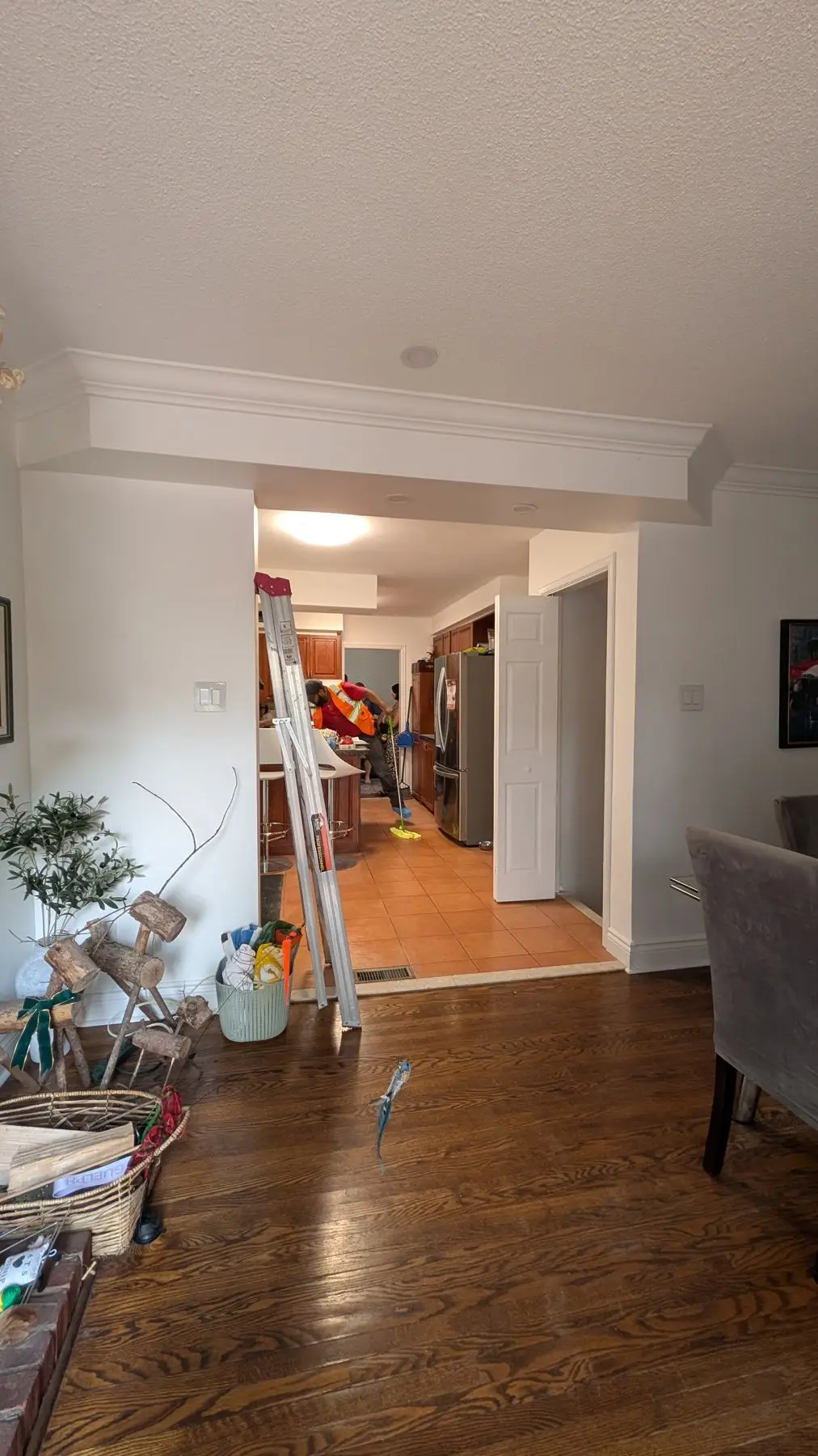 Finishing — Worker cleaning kitchen floor during finishing stage, viewed through a doorway from the dining area.