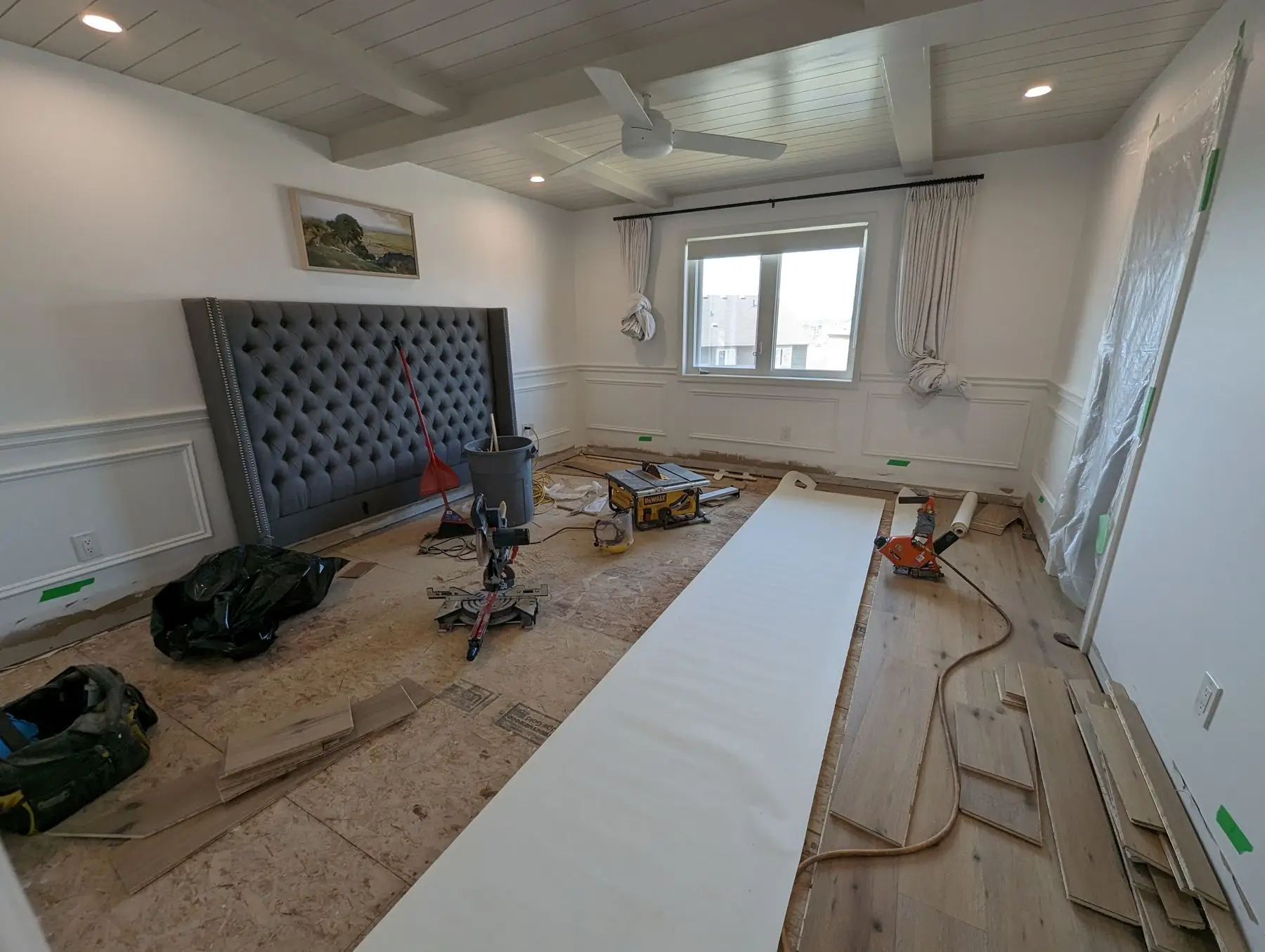 Finishing — Bedroom undergoing flooring installation with tools and materials scattered across subfloor.