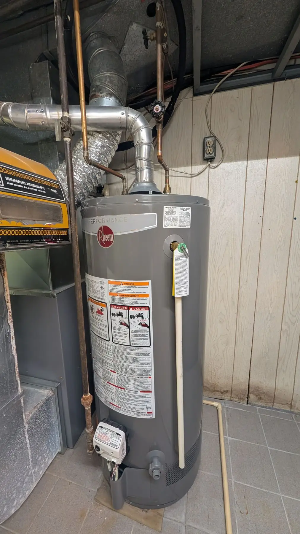 Finished — Basement mechanical room showing a Rheem water heater with connected copper piping, exhaust flue, and adjacent furnace.