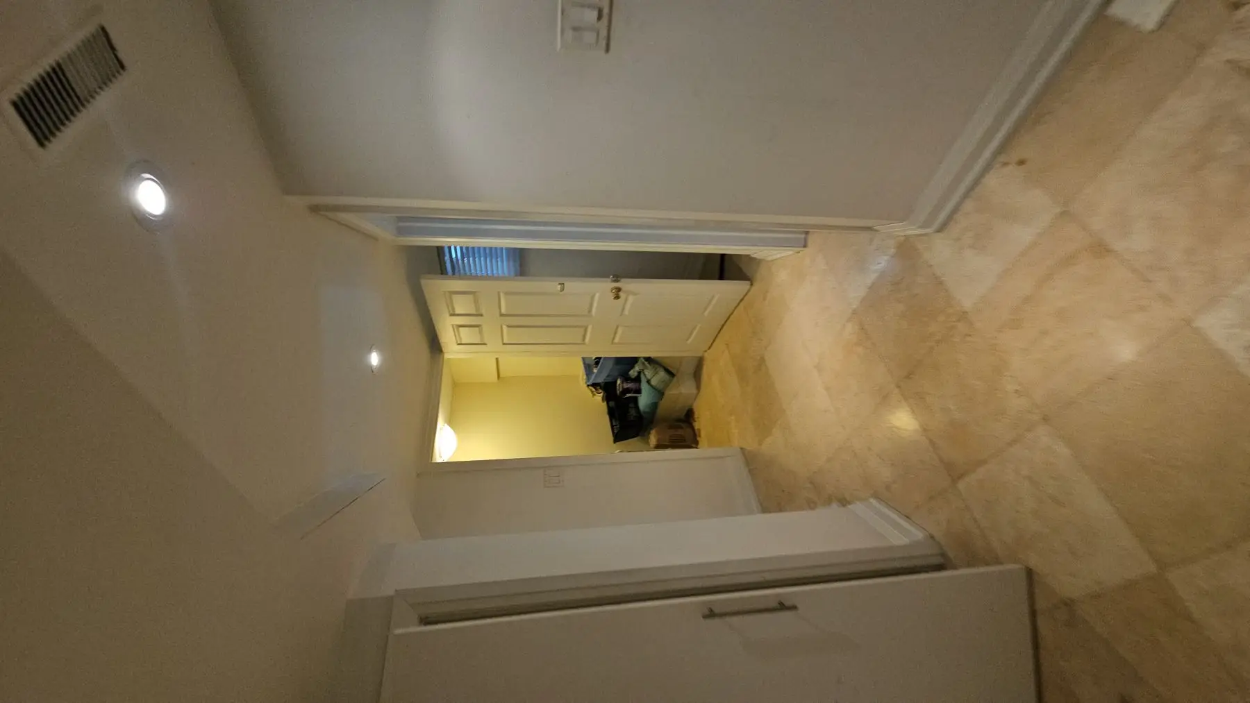 Finished — View through a doorway into a hallway with tile flooring and white walls.