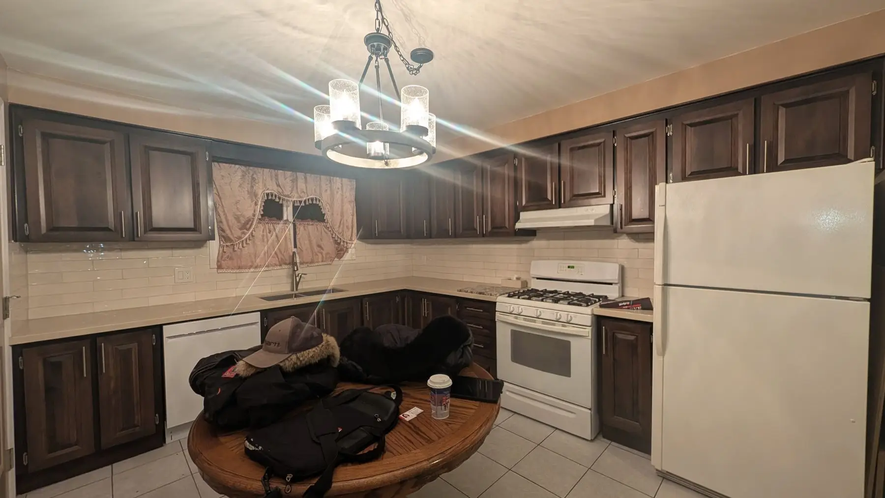 Finished — Finished kitchen with dark wood cabinets, white appliances, and a central table with personal items.