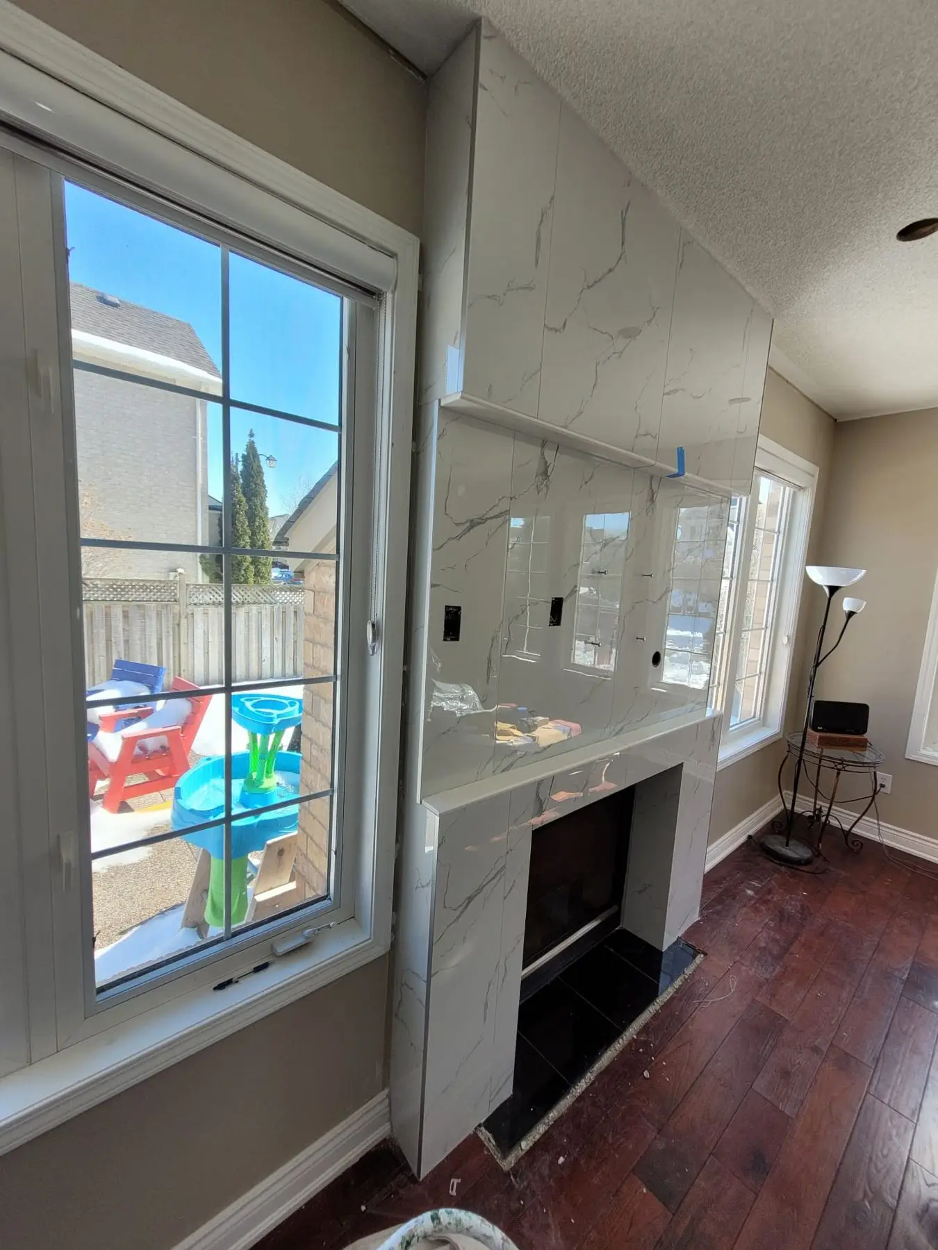 Finishing — Marble-look tile installation on living room fireplace surround with adjacent large window.