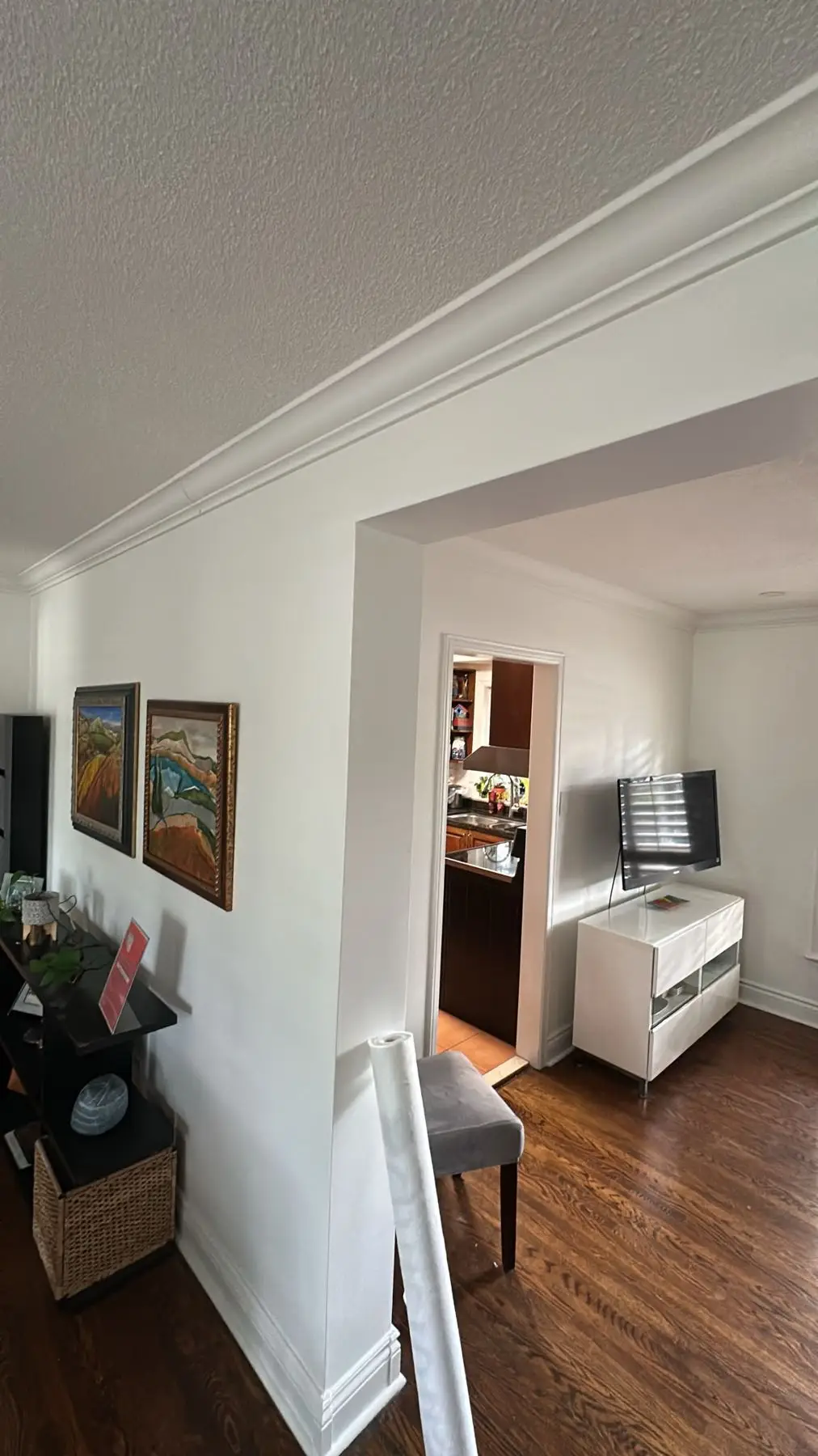 Finished — View through an arched doorway showing finished living space with hardwood floors and crown molding.