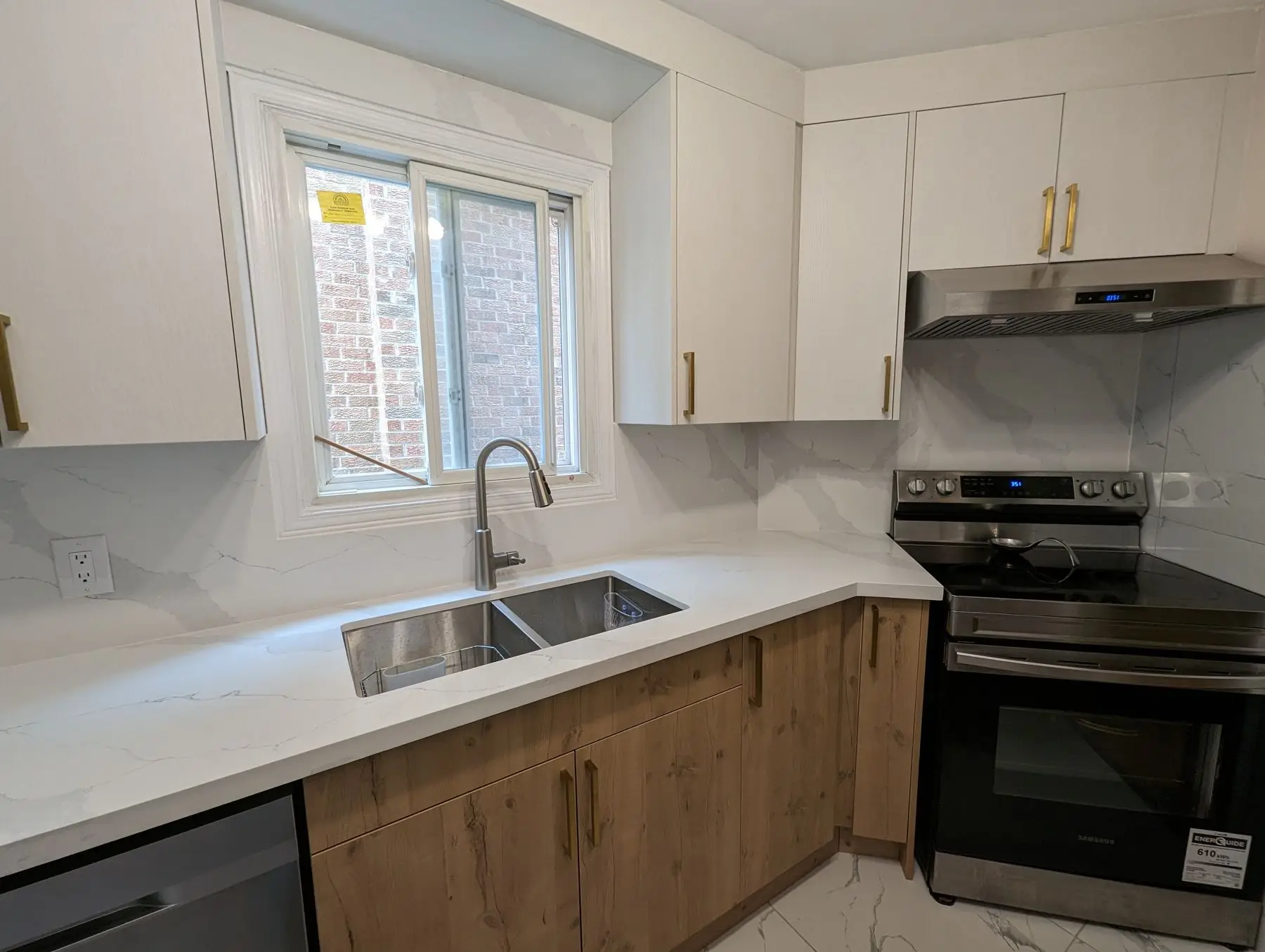 Finished — Finished kitchen corner featuring white and wood-grain cabinets, quartz countertops, double undermount sink, and stainless steel range.