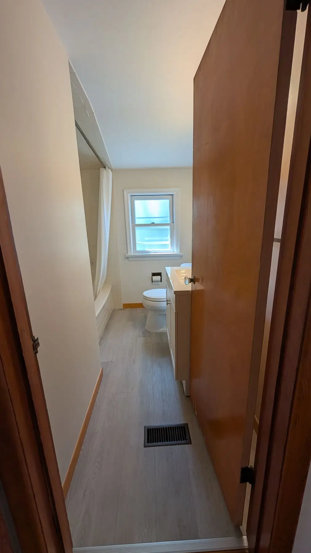 Finished — View through doorway into a finished small bathroom with vanity, toilet, and tub.