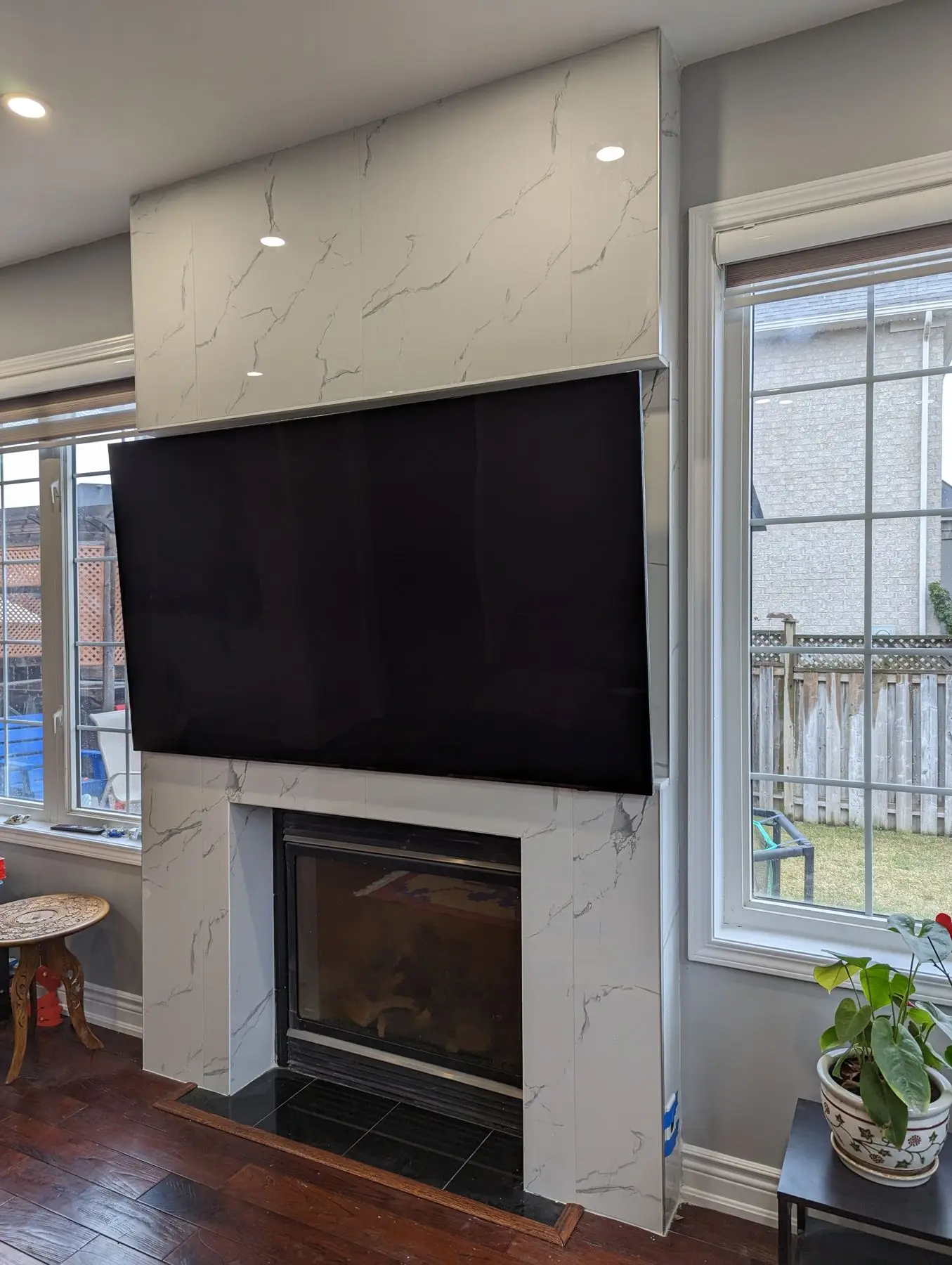 Finished — Finished living space featuring a marble-tiled fireplace surround with a mounted television and flanking windows.
