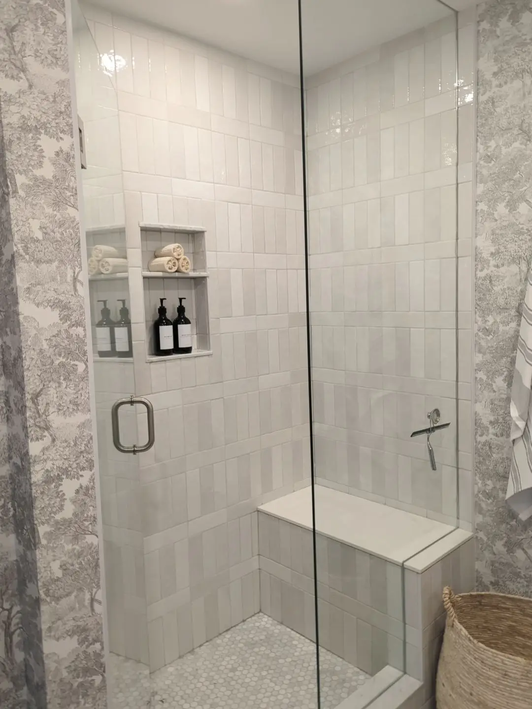 Finished — Finished tiled shower featuring a built-in bench, double niche, glass door, and patterned wallpaper exterior.